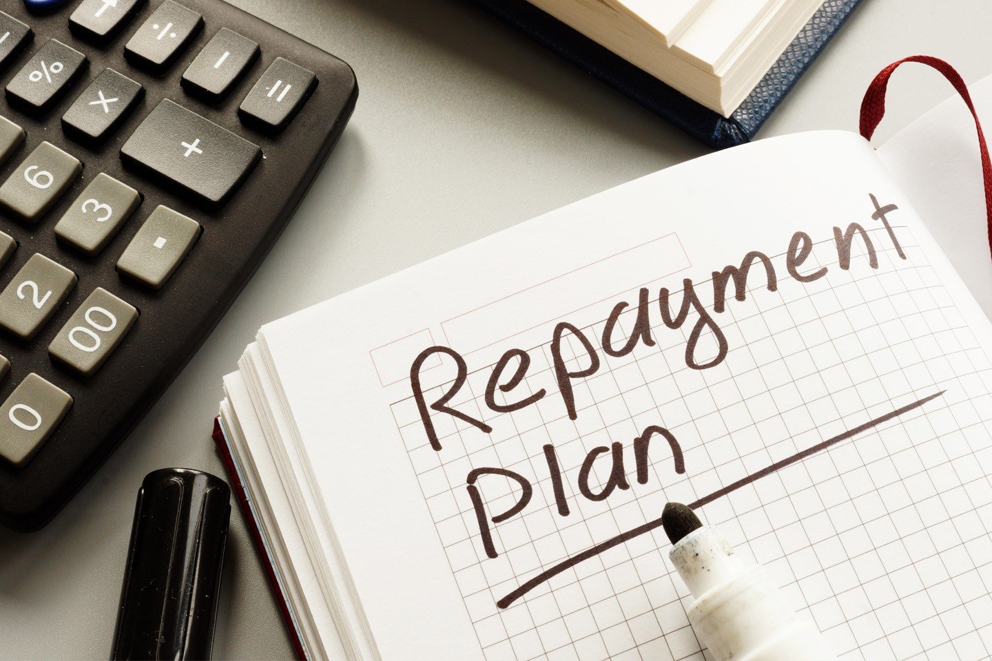 The image depicts a workspace with a calculator, a notebook labeled "Report plan," and a marker, suggesting planning and organization for a financial or business report.