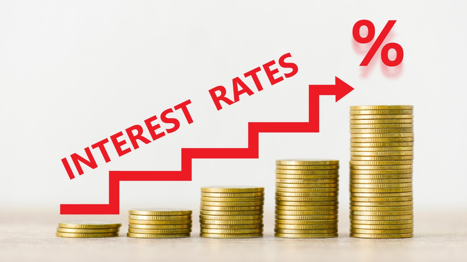 The image illustrates the increase in interest rates over time, depicted by stacks of coins growing taller with an upward arrow and the percentage symbol.