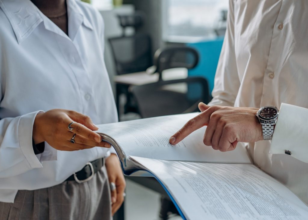 Two professionals are discussing or reviewing documents in an office setting.