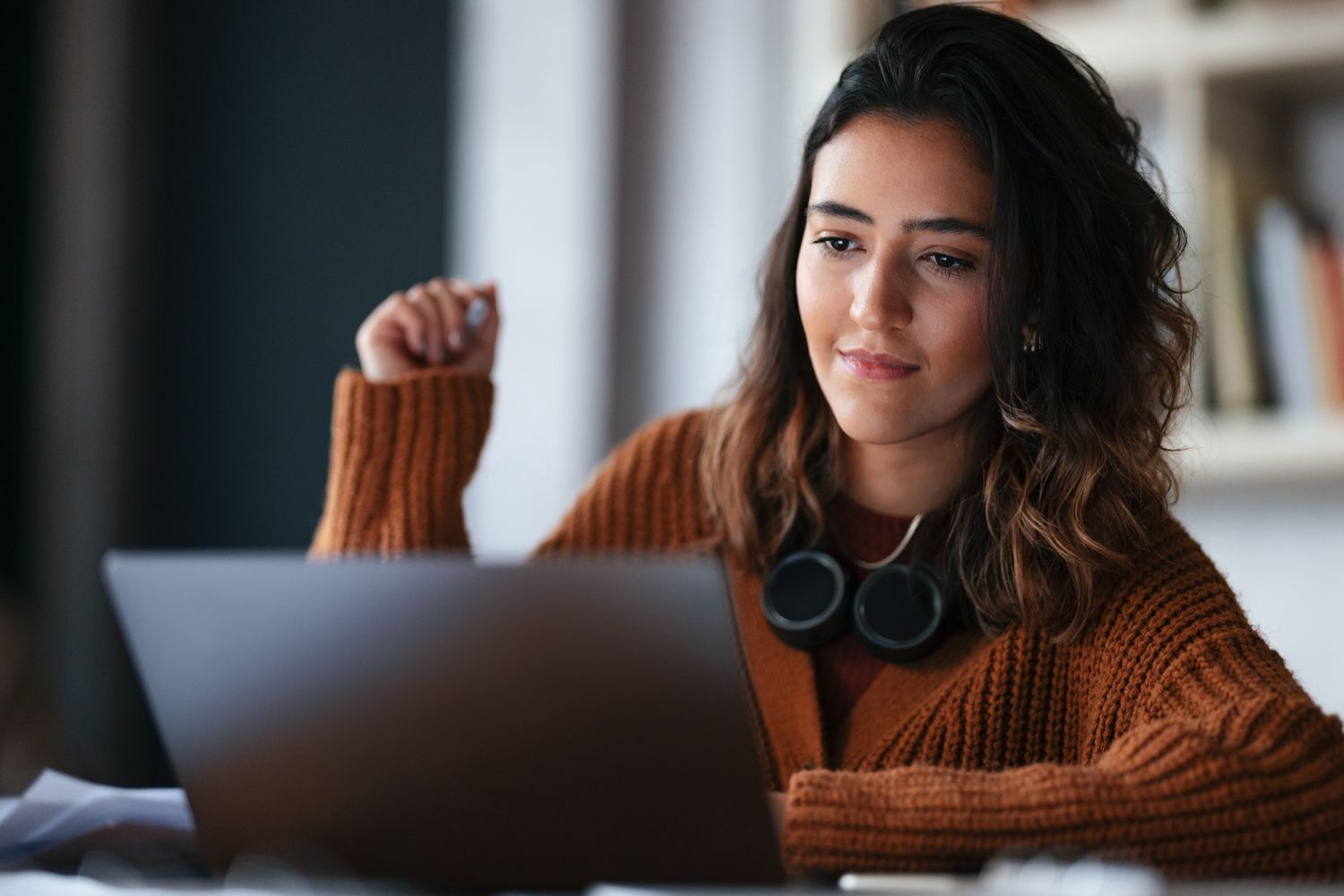 A woman working on a laptop, appearing focused and confident, possibly engaged in an online task or study.