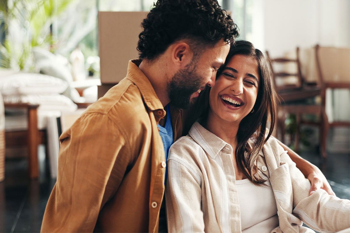 The picture shows a joyful moment between a couple sharing a laugh and enjoying each other's company indoors.
