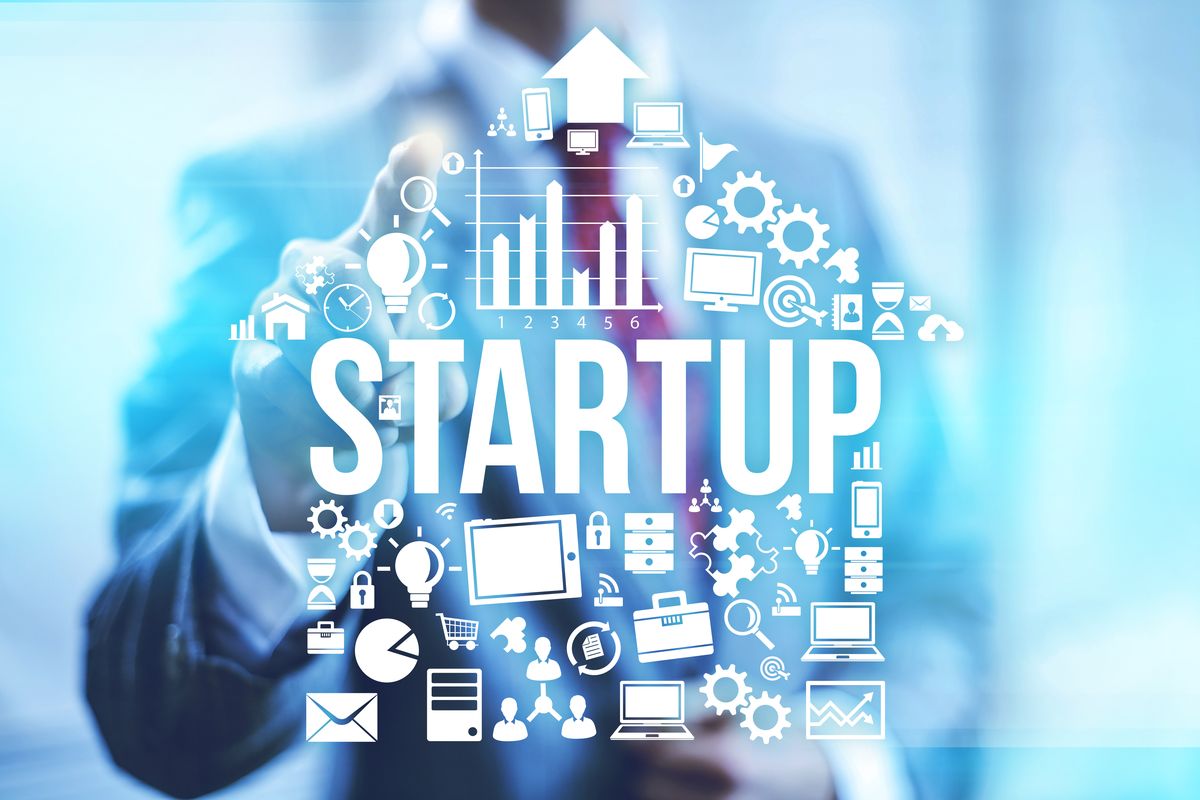 A person interacting with a digital graphic representing various aspects of a startup, with the word "STARTUP" prominently displayed in the center.
