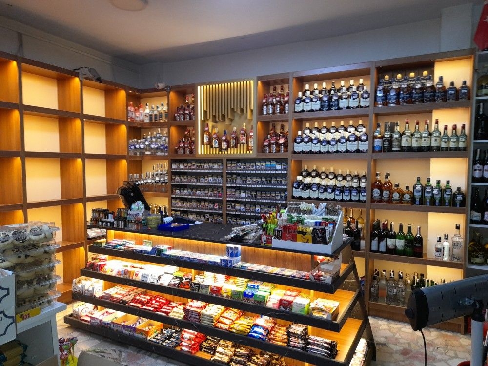 A small liquor and snack shop with shelves stocked with bottles of alcohol and a display of various confectioneries.