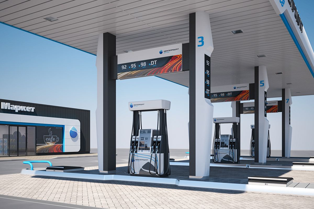 A modern fuel station with multiple pumps and digital screens, with a convenience store in the background.