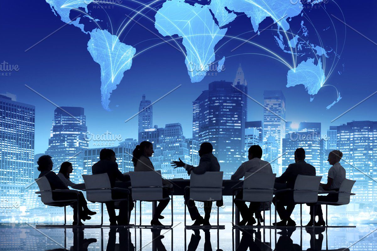 A team of business professionals having a discussion in a modern conference room with a digital world map and city skyline in the background.