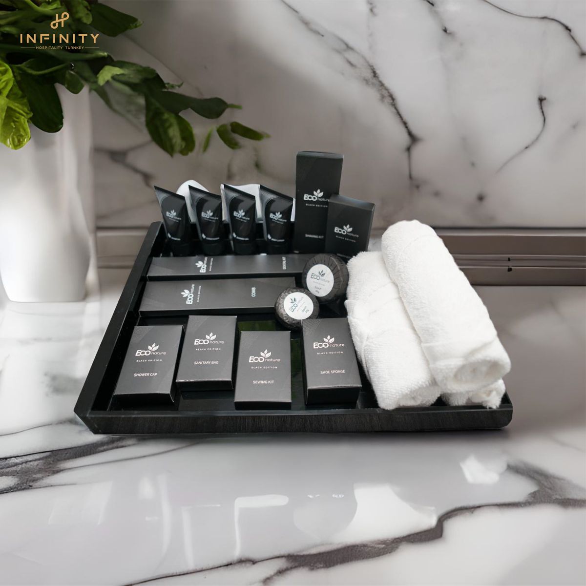 A neatly arranged set of eco-friendly toiletries and rolled towels on a black tray in a luxurious bathroom.