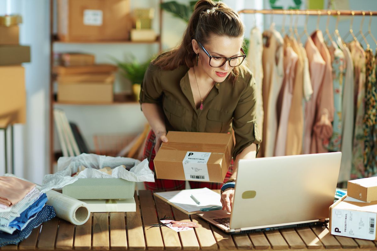 Woman entrepreneur packing customer orders while managing her online store, representing financing for women-owned businesses to support growth and daily operations.