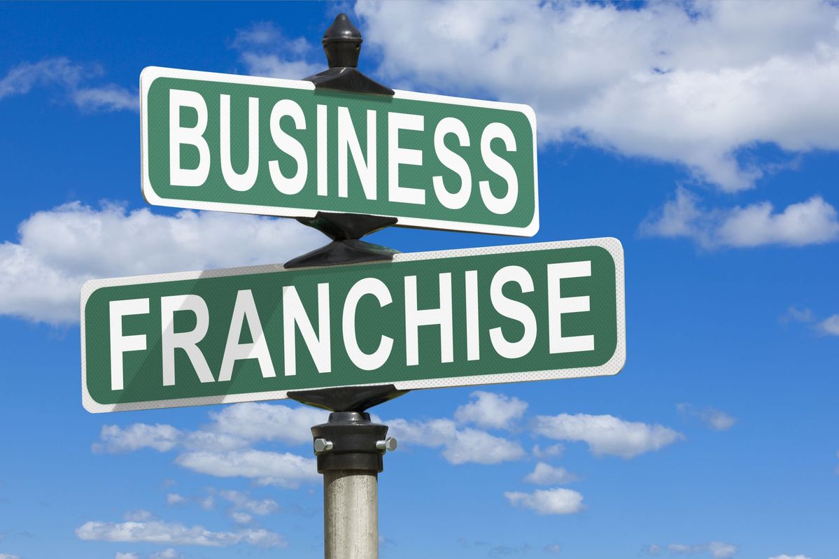 Street sign pointing to business and franchise directions against blue sky, representing small business loans and financing options for franchise owners.