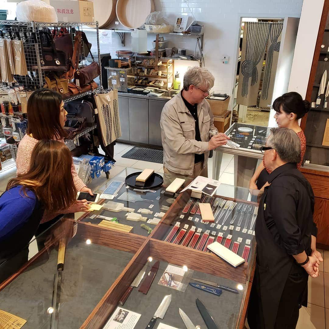Restaurant staff and customers gathered around a retail counter displaying kitchen tools and equipment, representing restaurant businesses using payment systems and tools that support merchant cash advances and flexible financing solutions.