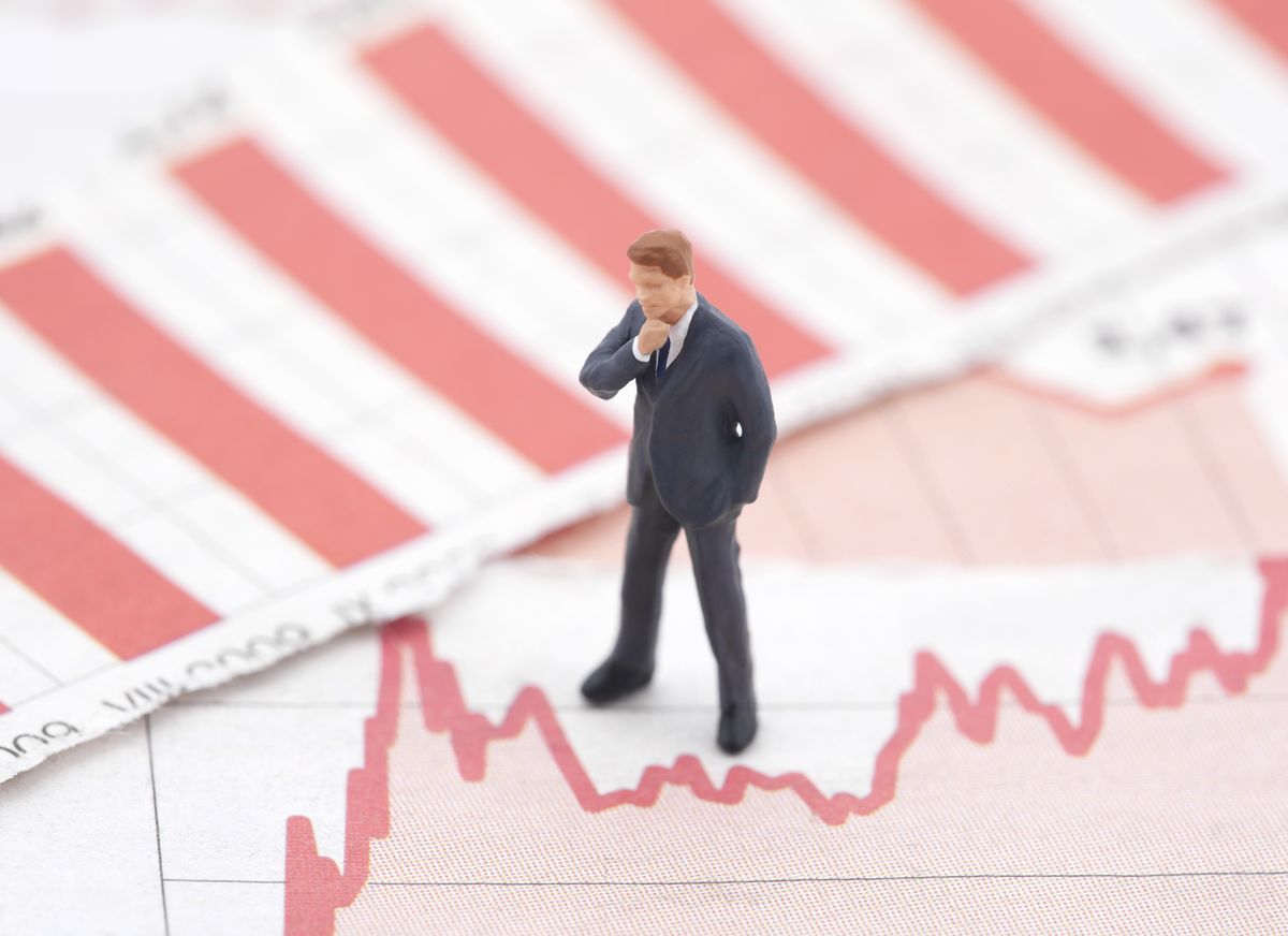 Business figure standing on declining financial charts, representing cash flow challenges and funding solutions through a Merchant Cash Advance in North Carolina.